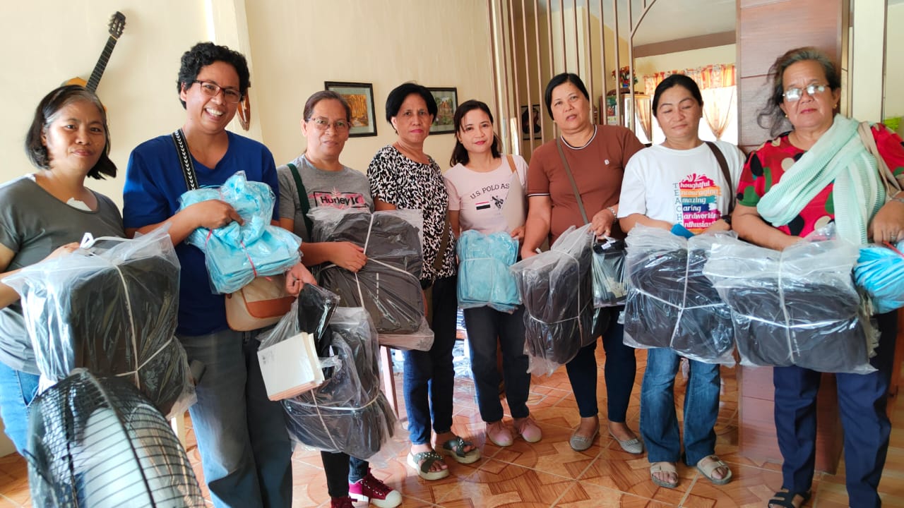 Two teachers smiling as they hold bundles of donated school supplies for their students, handed over by ForAnother.