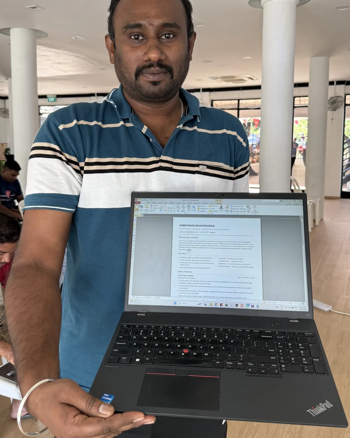 A learner holds up a laptop to show a page they built