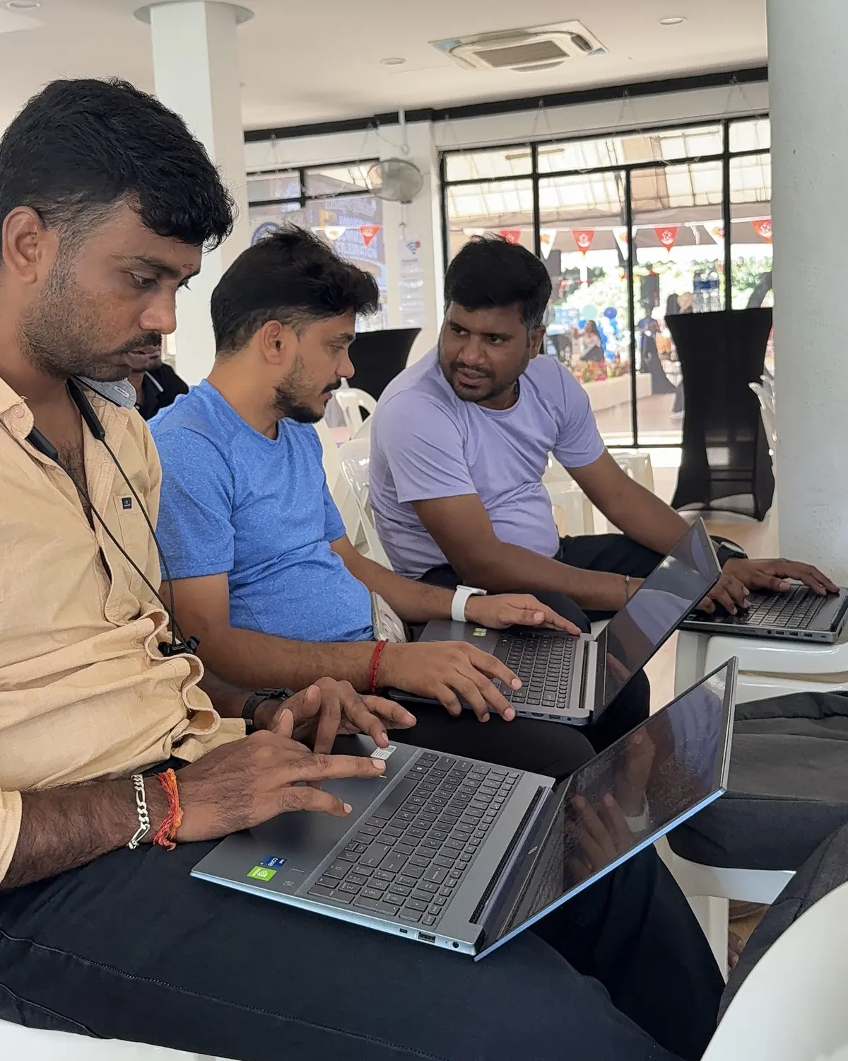Three learners sitting side by side, typing on laptops