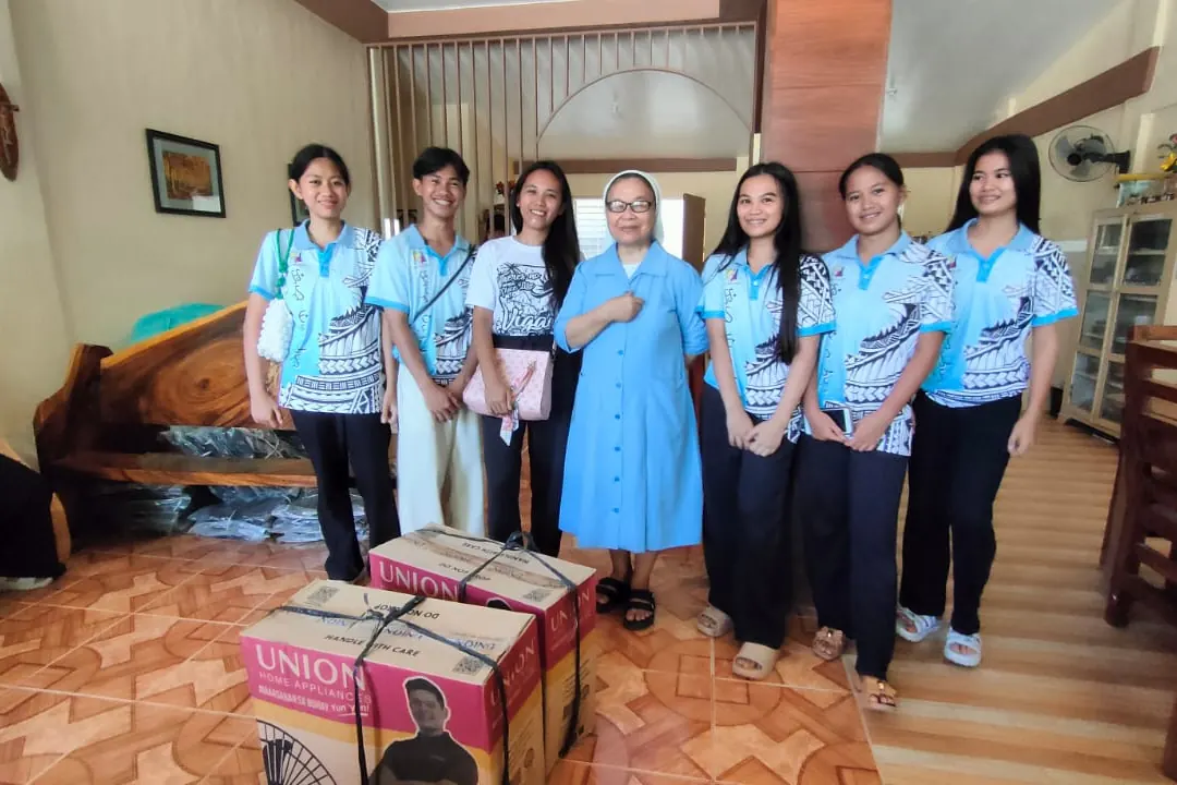 Volunteers standing together indoors beside boxes of supplies