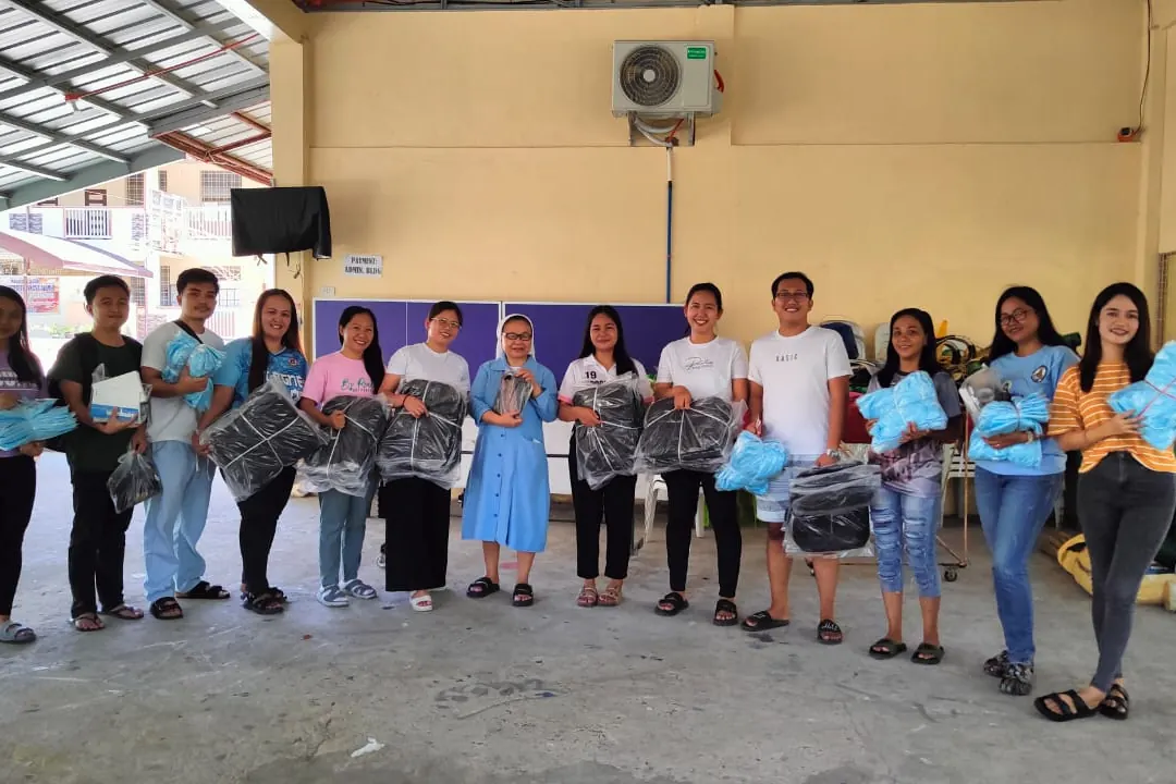 A line of volunteers and students holding kits in a school hall