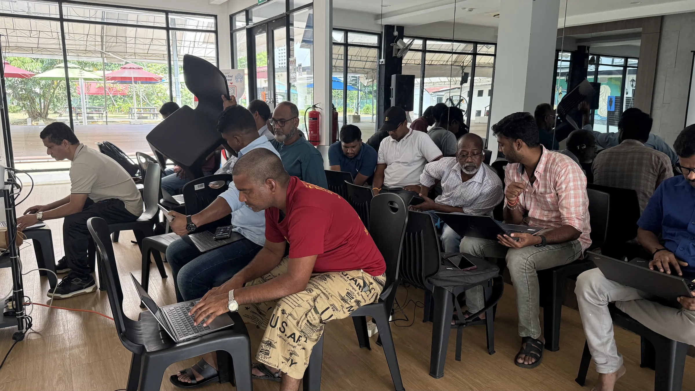Learners on black chairs working on laptops in a bright hall in Sembawang