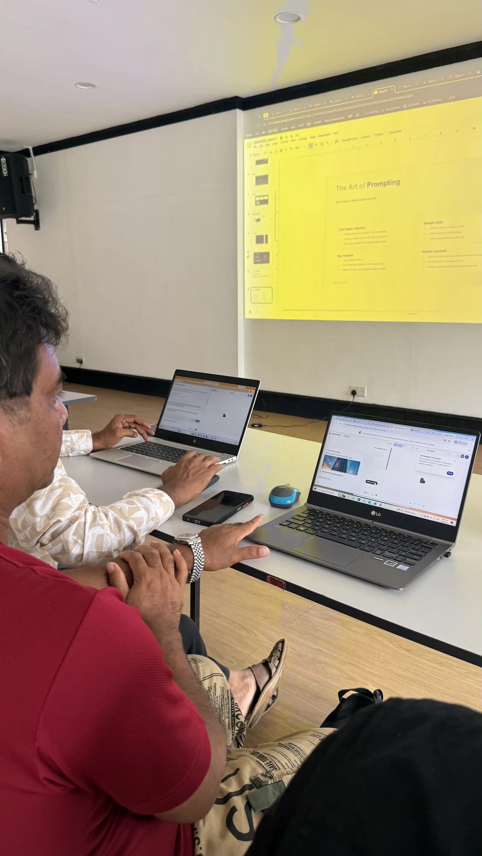 Two learners at a table typing on laptops