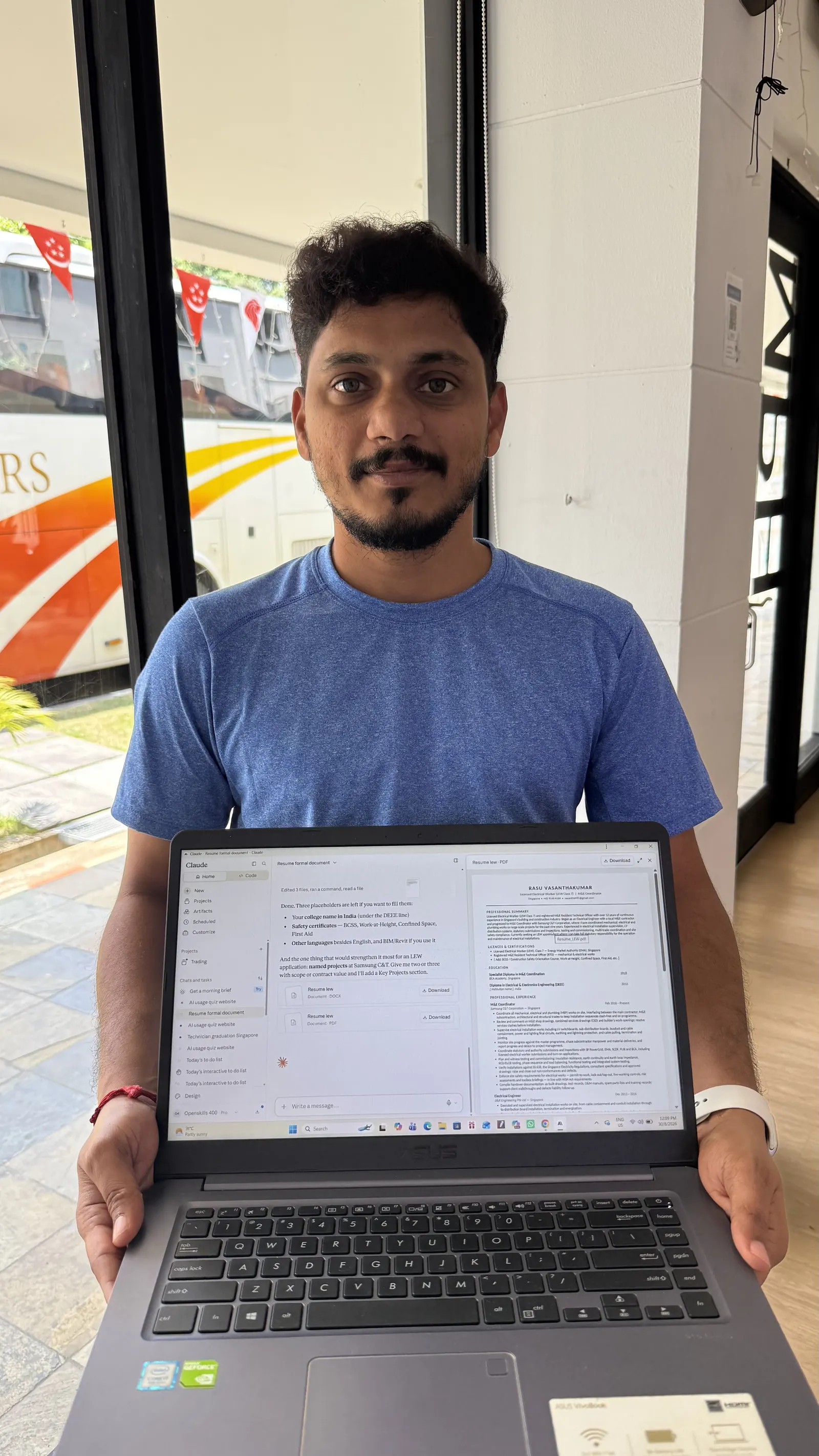 A learner in a blue shirt holds up a laptop showing a document