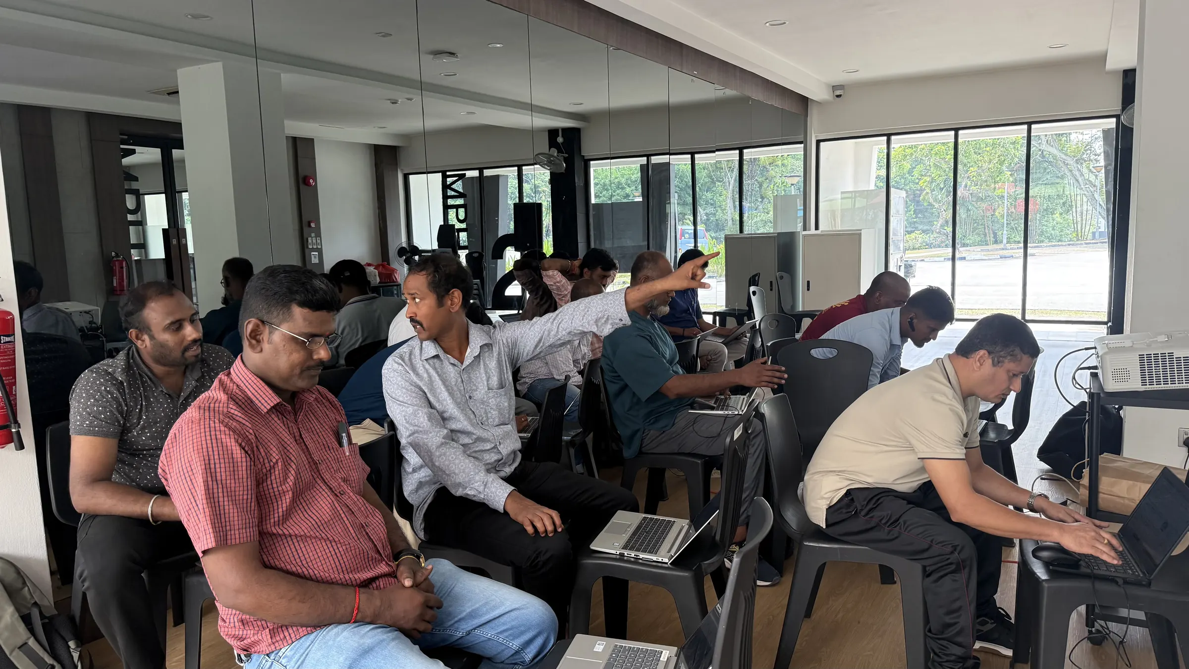 Rows of learners on black chairs, each working on a laptop
