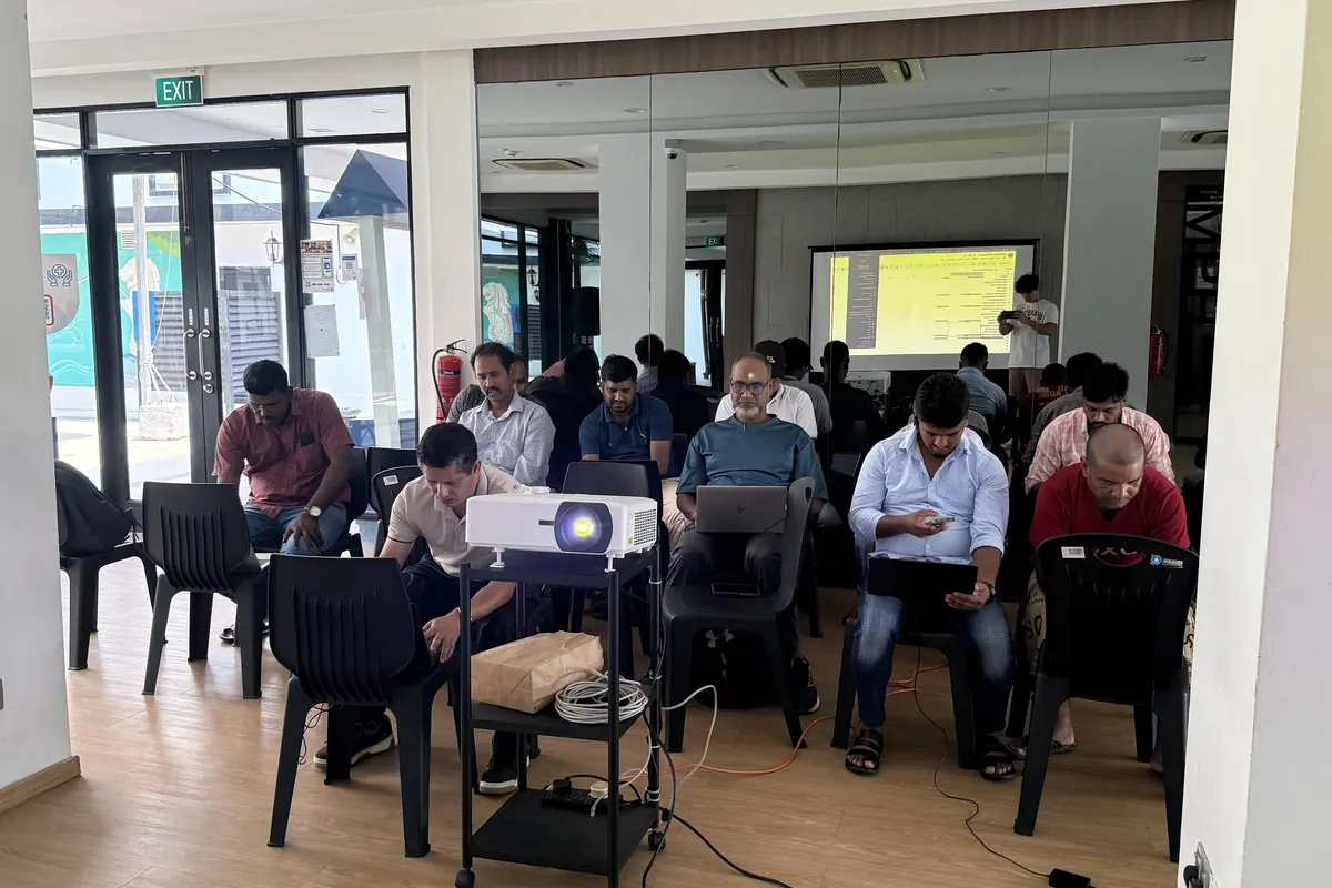 Learners seated in rows with laptops, facing a projected slide
